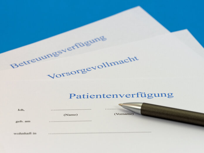 Auf einem Tisch liegen eine Patientenverfügung, eine Vorsorgevollmacht und eine Betreuungsverfügung, darauf liegt ein Stift.