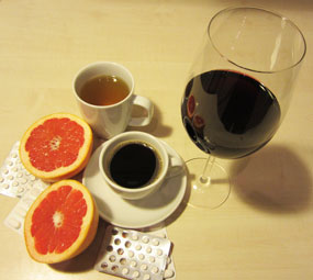 Aufgeschnittene Grapefruit, neben einer Tasse Tee, einer Tasse Kaffee und einem Glas Rotwein.